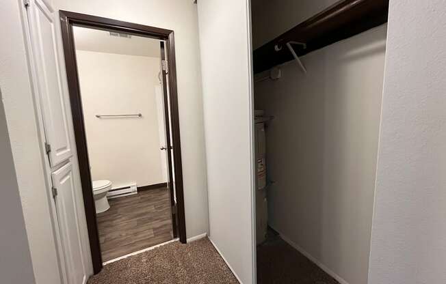 an open door leads to a bathroom with a toilet and a closet