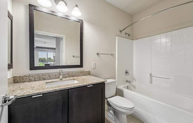A bathroom with a sink, mirror, toilet and bathtub.