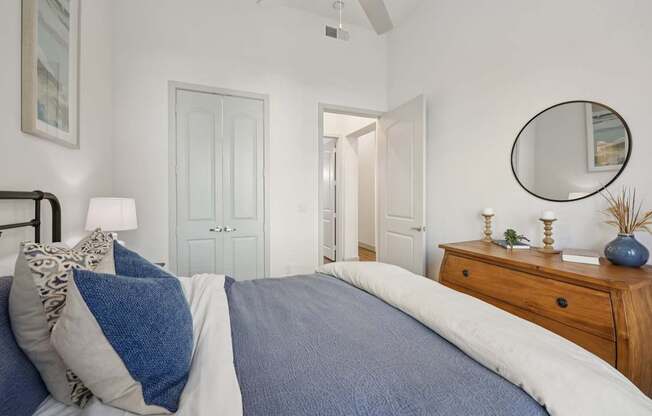 A bedroom with a bed, a dresser, and a mirror.