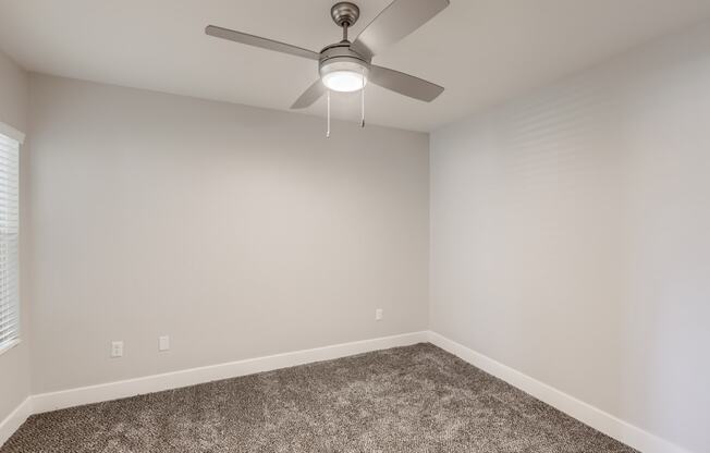 a bedroom with a ceiling fan and carpet