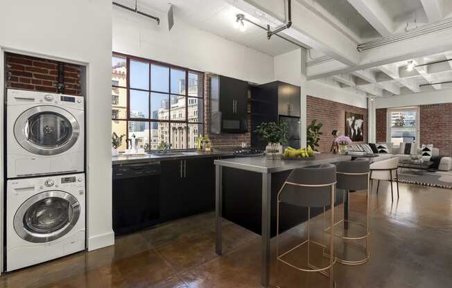 a kitchen with a washing machine and a kitchen island with chairs and a counter top