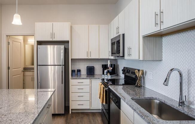 a kitchen with granite counter tops and a stainless steel refrigerator
