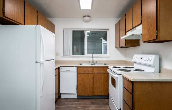 an empty kitchen with white appliances and wooden cabinets