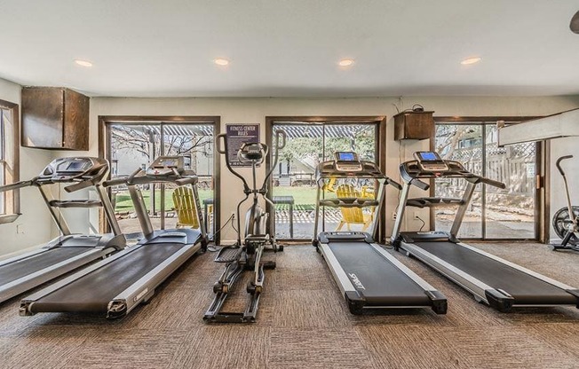 a gym with cardio equipment and windows