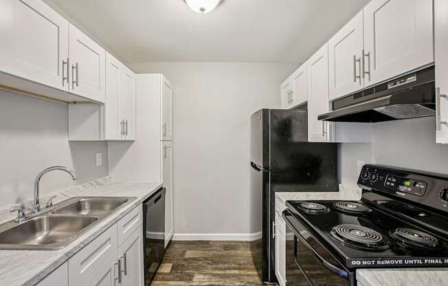 A kitchen with a black fridge and stove top oven.