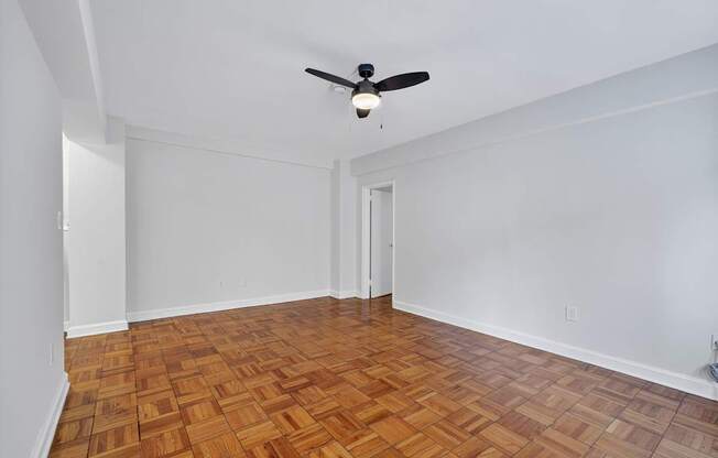 A room with a ceiling fan and wooden flooring.