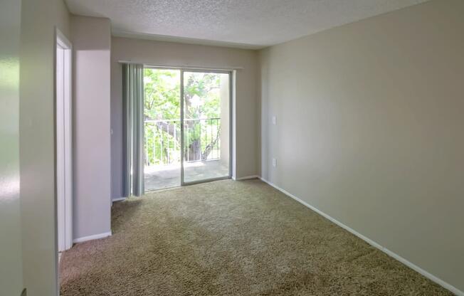 an empty living room with a sliding glass door to a patio