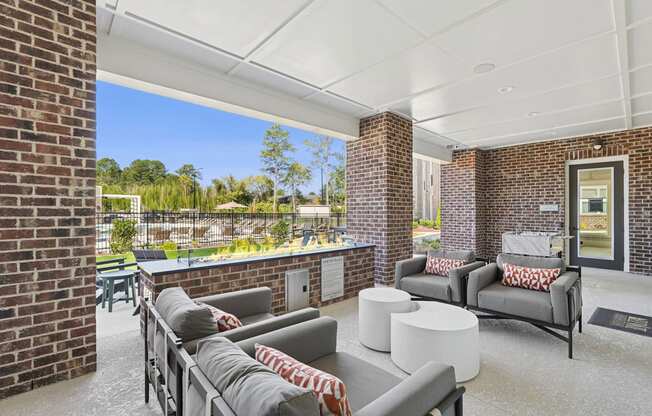 A patio with a white couch and a grey couch with a red and white throw on it.