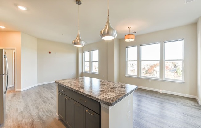 view of kitchen with island and vacant living area with large windows and hardwood floors at city view apartments in washington dc