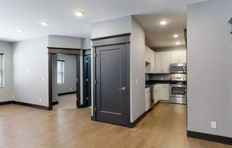 a kitchen and living room with a hardwood floor and grey walls