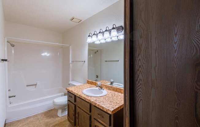 a bathroom with a sink and a toilet and a mirror. Fargo, ND Plumtree Apartments