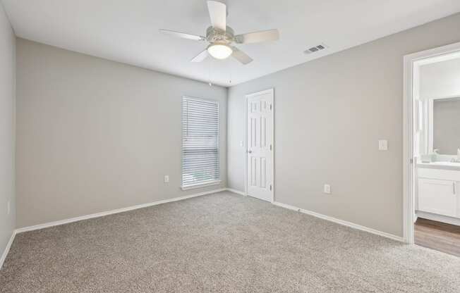 A room with a ceiling fan and carpeted floor.