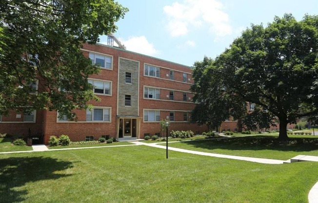 A red brick apartment building with a tree in front.