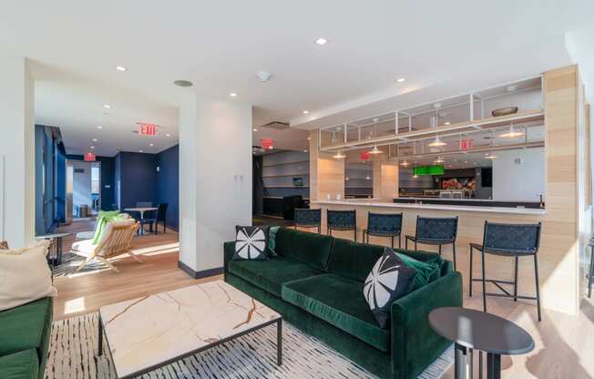 a living room with a green couch and a bar with chairs