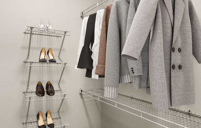 A closet with a coat hanging on a rod and a shelf with shoes.