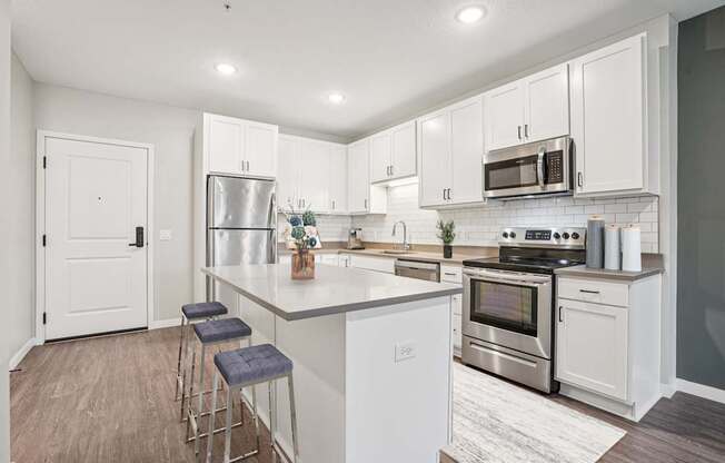 A kitchen with white cabinets and a white island.
