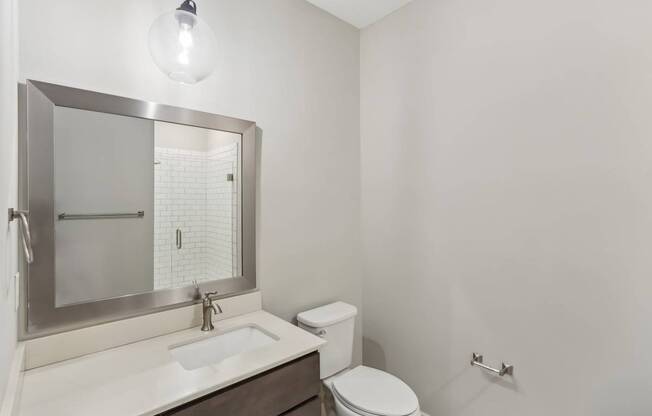 A white bathroom with a toilet, sink, and mirror.