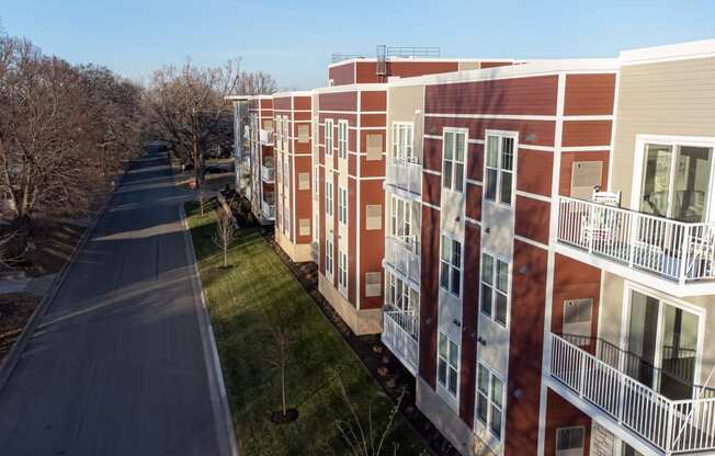 a row of red and white buildings with balconies and a road