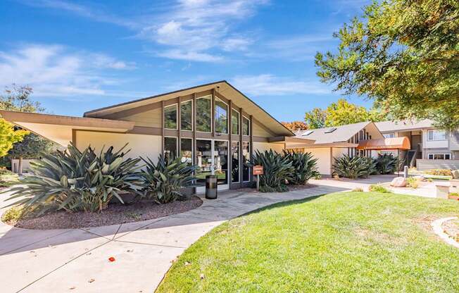 A modern building with a glass entrance and a landscaped front yard.