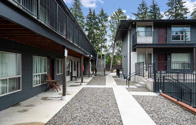 A long, narrow walkway with a black railing separates two buildings.
