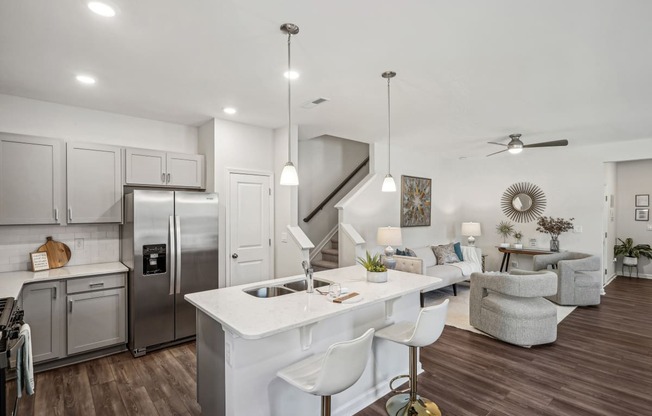 a kitchen and living room with a white counter top and a stainless steel refrigerator