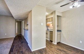 the living room and kitchen of an apartment with a hard wood floor