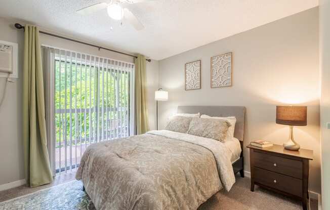 a bedroom with a bed and a sliding glass door to a balcony