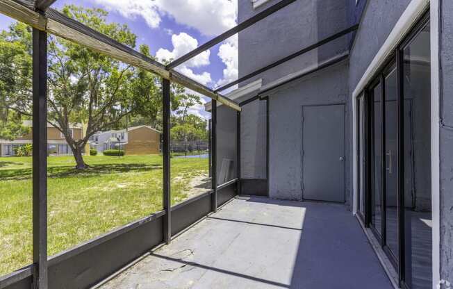 the patio of a building with glass doors and a grass field