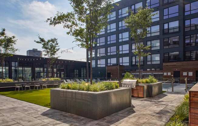 A modern building with a large glass facade and a courtyard with concrete planters and greenery.
