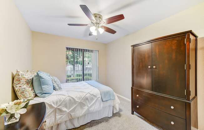 A bedroom with a bed, dresser, and ceiling fan.