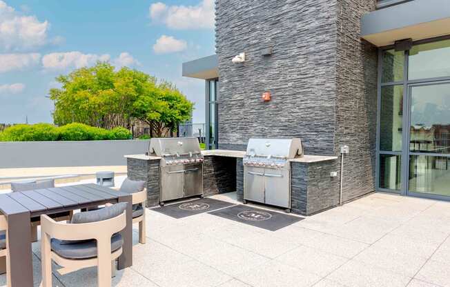 A patio with a table and chairs and a grill.
