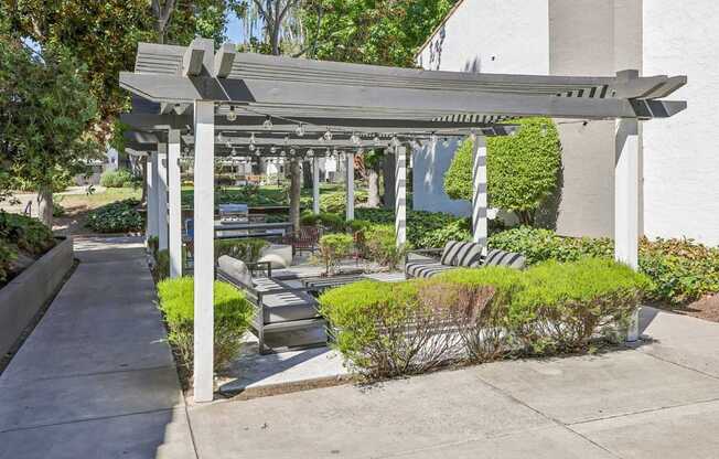 A white pergola with a bench underneath it.