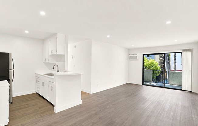 A kitchen with white cabinets and a wooden floor.
