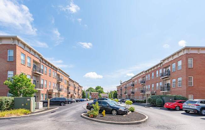 A sunny day in a residential area with cars parked on the street and apartment buildings on either side.
