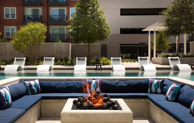 a swimming pool with blue lounge chairs and a fire pit