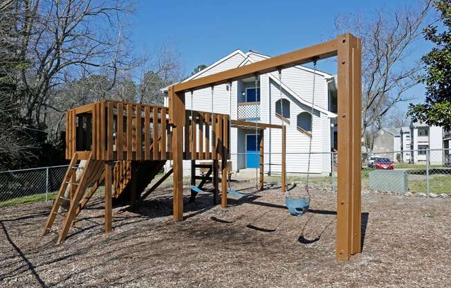 a playground with a swing set in front of a house