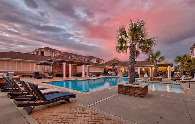 our resort style swimming pool with lounge chairs and palm trees at our hotel at Nexus at Sandhill, Columbia, SC 29229