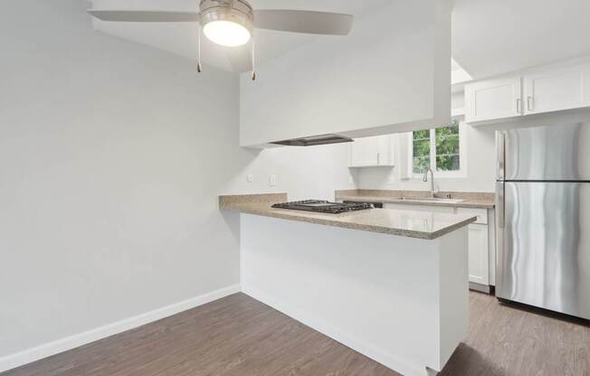 A modern kitchen with a white countertop and a ceiling fan.