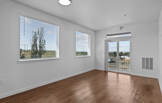 a bedroom with hardwood floors and a door leading to a balcony