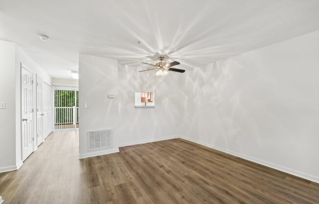 a living room with white walls and a ceiling fan