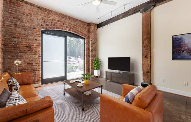 a living room with leather furniture and a brick wall