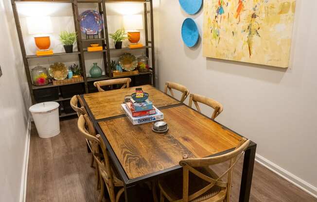 a dining area with a wooden table and chairs and a large painting on the wall