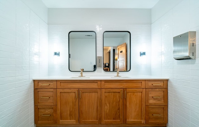 two mirrors on top of a bathroom counter with two sinks