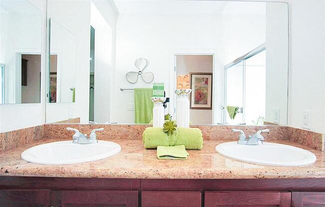 A bathroom with two sinks and a green towel.