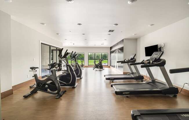 a gym with treadmills and a tv on the wall