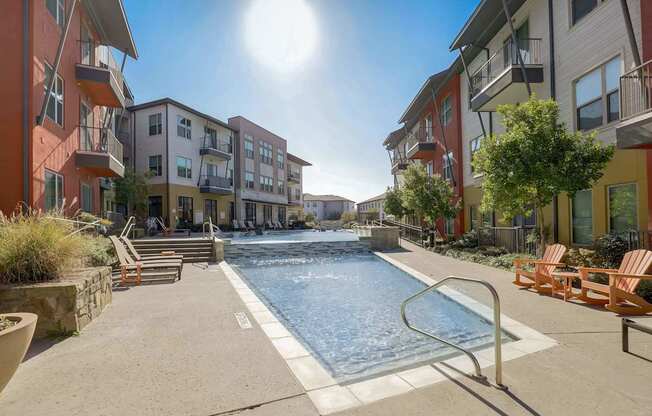 A sunny day at a pool surrounded by apartment buildings at Infinity on the Point Apartments, Texas, 75243
