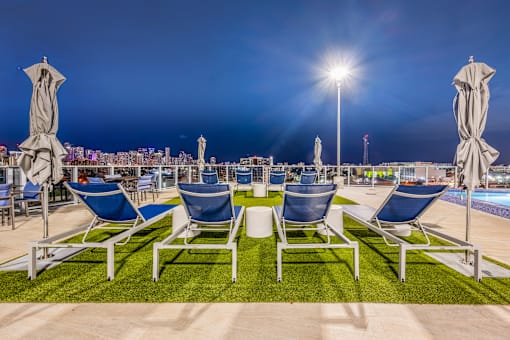 a row of chairs and tables with umbrellas near a pool