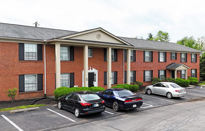 A black car is parked in front of a brick building.