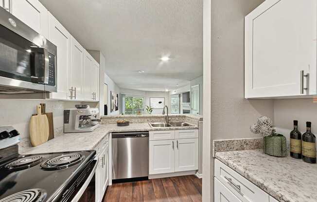 A modern kitchen with white cabinets and stainless steel appliances.