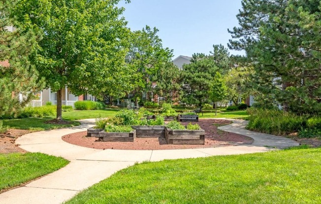 a sidewalk leading to a park with trees and benches